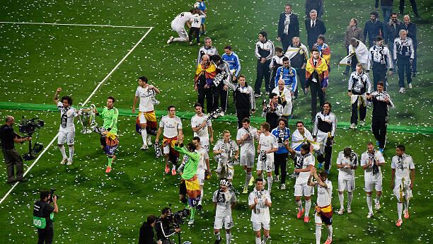 Real Madrid players celebrating on the pitch with the Champions League trophy