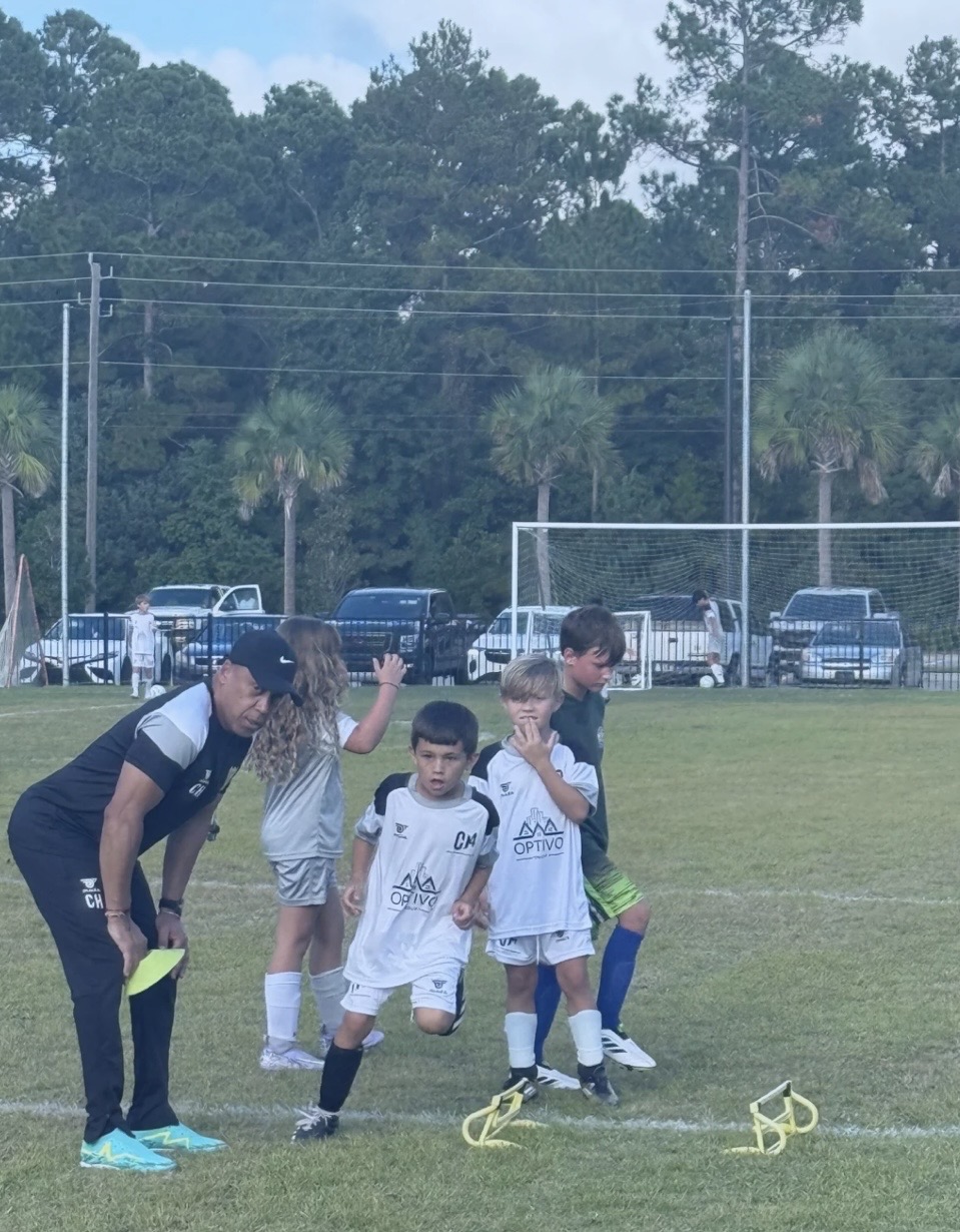 Young players work on movement over small hurdles with a CH4 coach